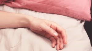 Adult's lower arm, wrist and hand resting on surface. Fingers and thumb are relaxed and slightly curled.